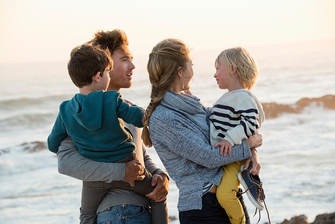 Happy young family enjoying on the beach at sunset