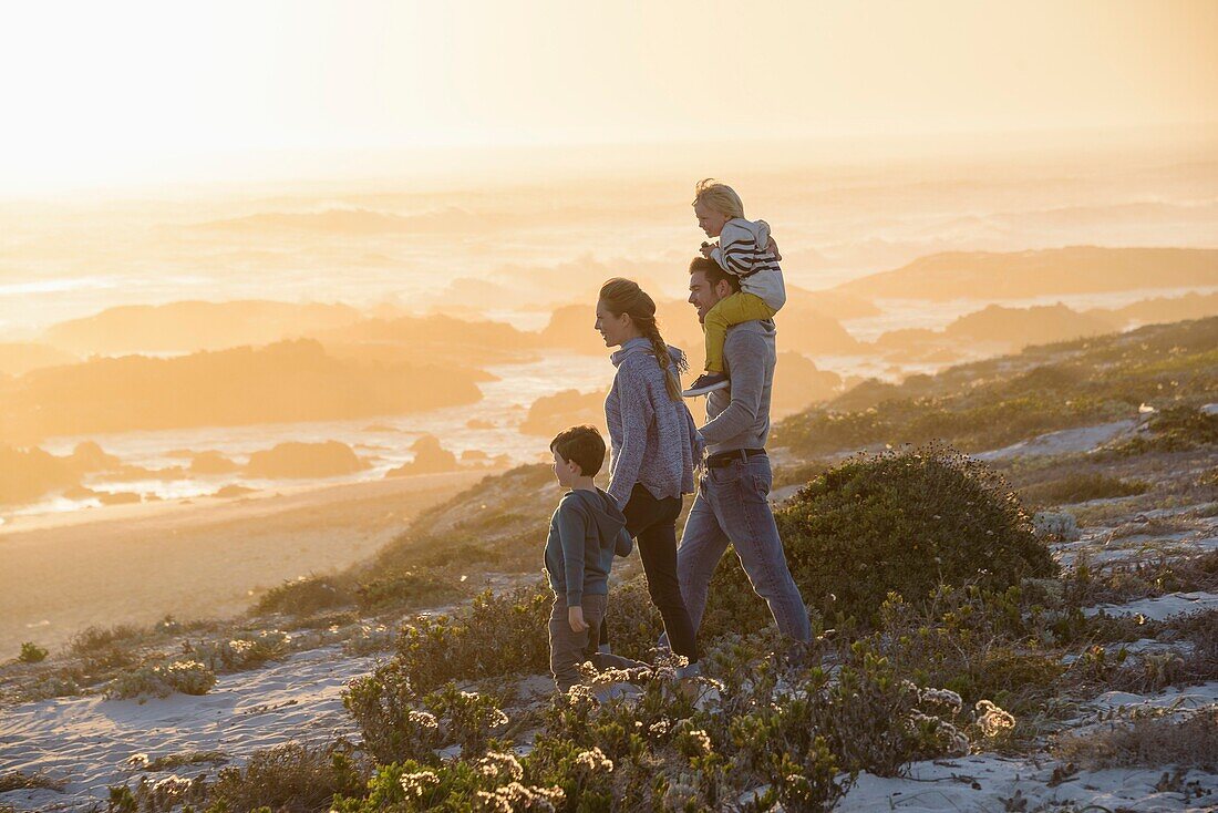 Happy young family walking on the beach at sunset