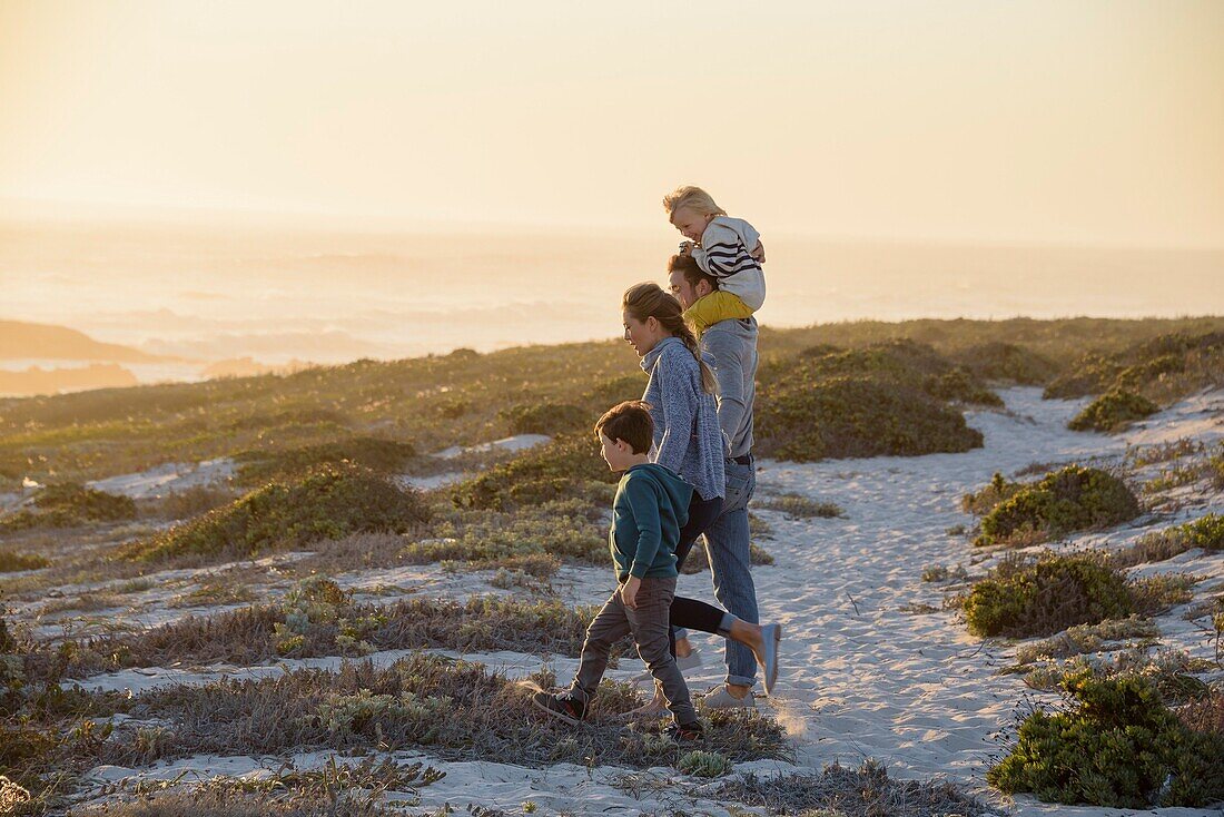 Happy young family walking on the beach at sunset