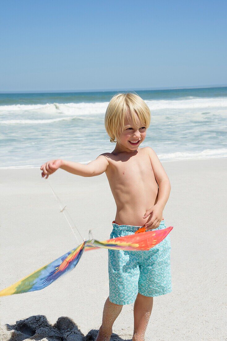Happy boy holding a kite on the beach
