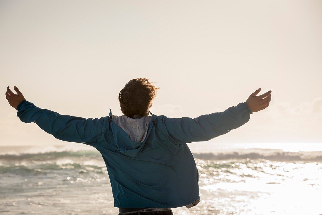 Happy young man with arm outstretched on beach