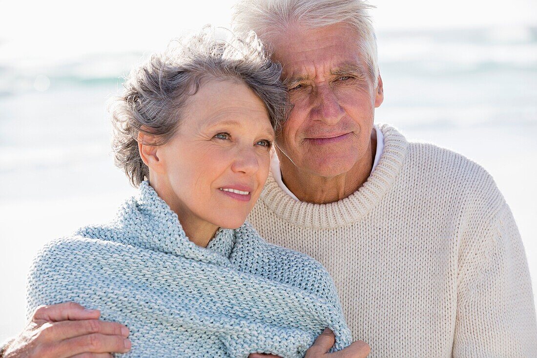 Elderly man embracing his wife from behind on the beach