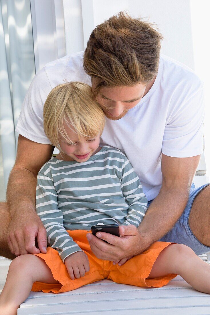 Happy father and son using phone
