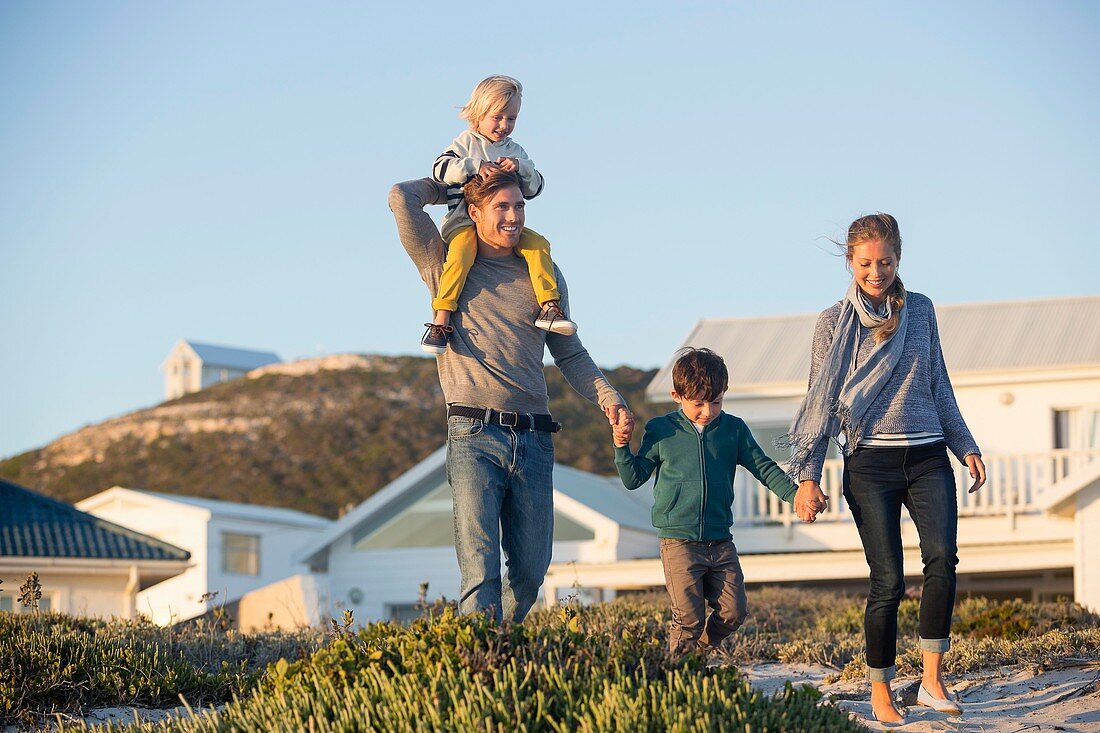 Happy couple with their children walking on the beach