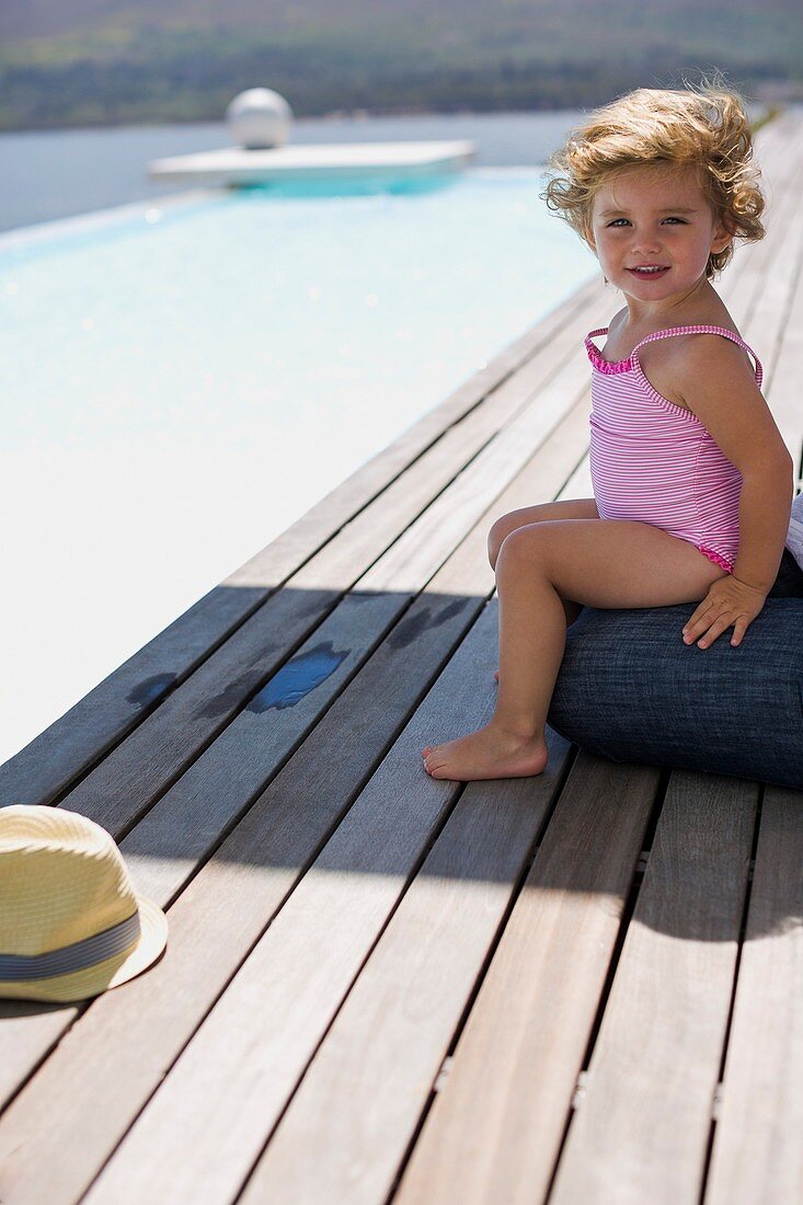 Happy baby girl sitting on a boardwalk