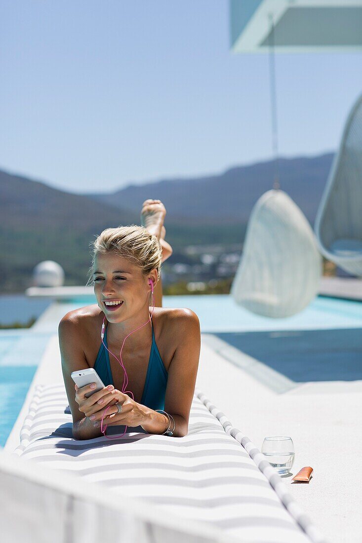 Young woman listening to music with smart phone at the poolside