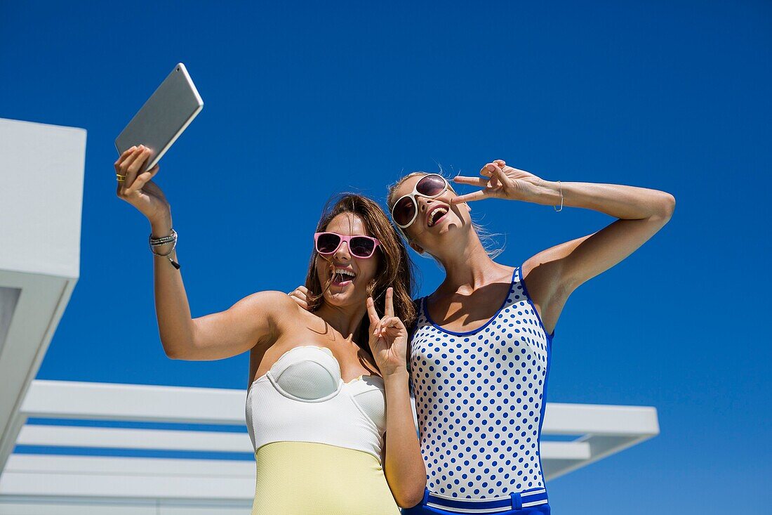 Happy friends taking selfie with a digital tablet