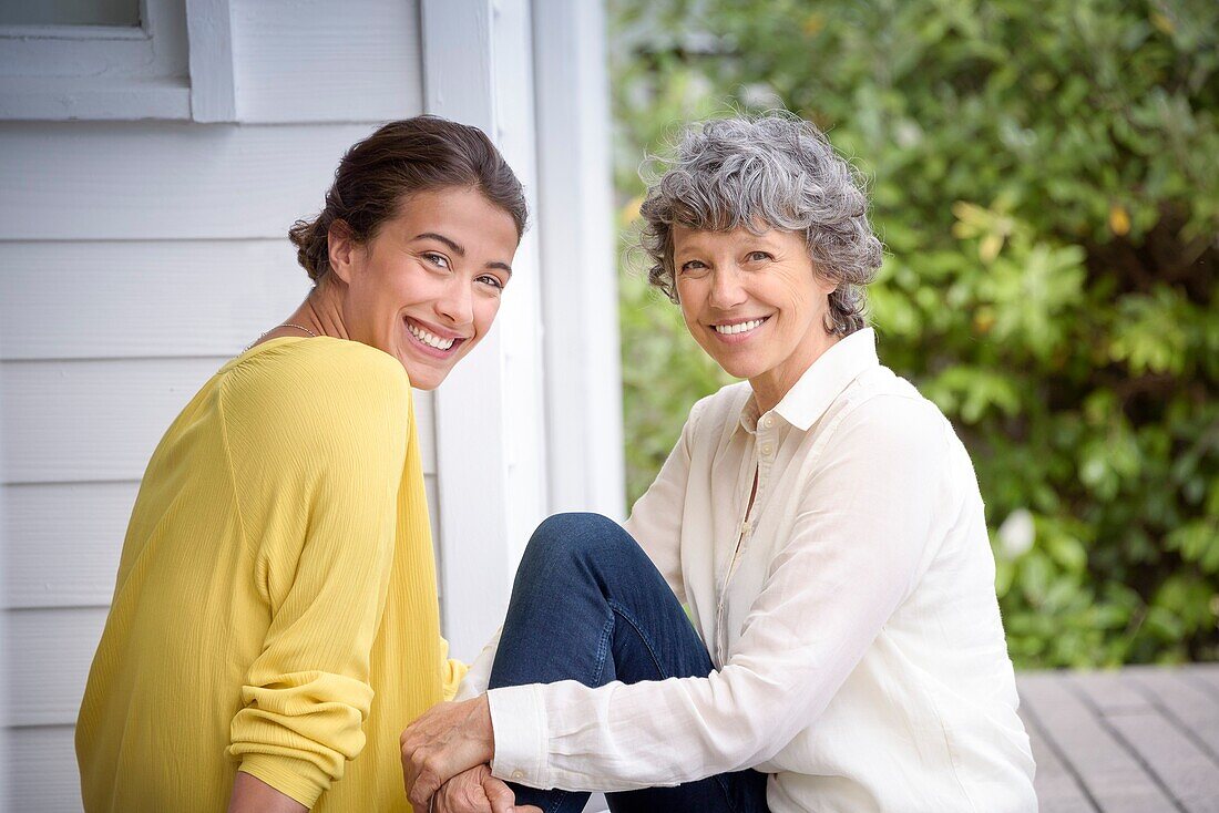 Porträt einer glücklichen Mutter, die mit ihrer erwachsenen Tochter auf einer Veranda sitzt