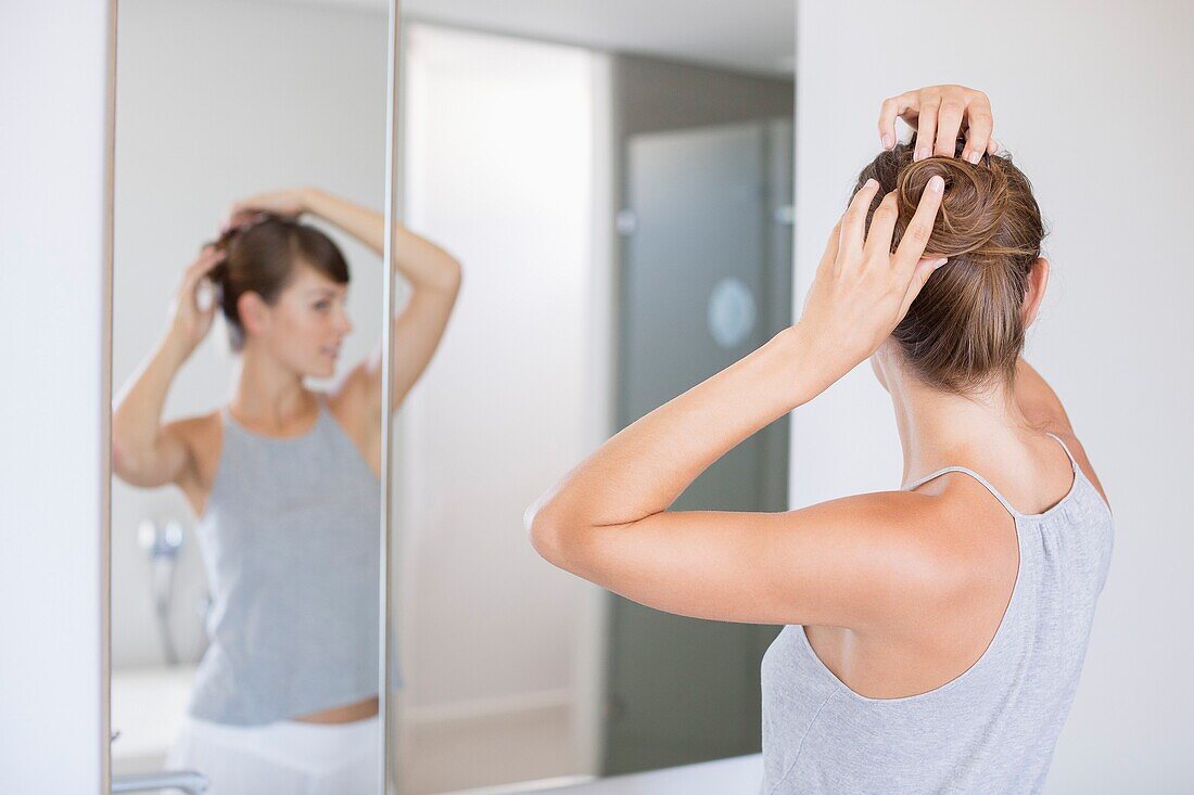 Young beautiful woman adjusting her hair in a bathroom
