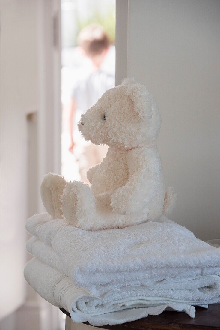Close-up of a soft toy on towels with child in background