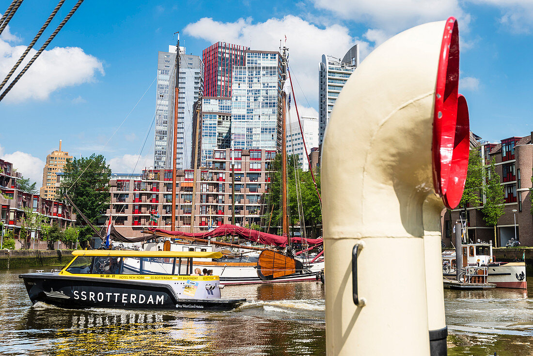 A water taxi coming into Leuvehaven with historical ships and residential and office high-rise buildings in the background, Rotterdam, Netherlands