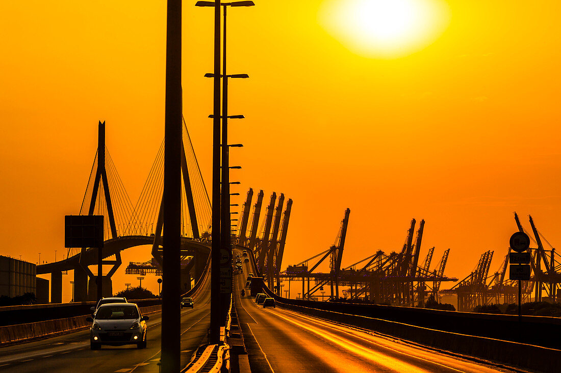 Die Köhlbrandbrücke im Hamburger Hafen, umringt von Containerkränen zum Sonnenuntergang, Hamburg, Deutschland
