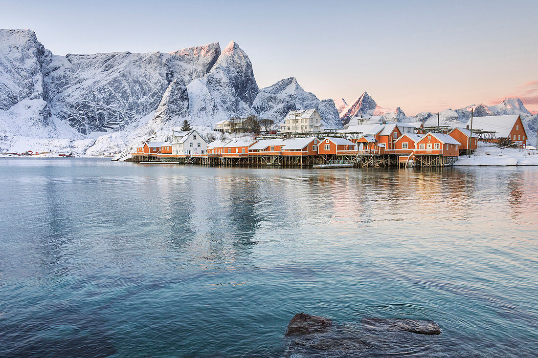The colors of dawn frame the fishermen's houses surrounded by snowy peaks, Sakrisoy, Reine, Nordland, Lofoten Islands, Arctic, Norway, Scandinavia, Europe