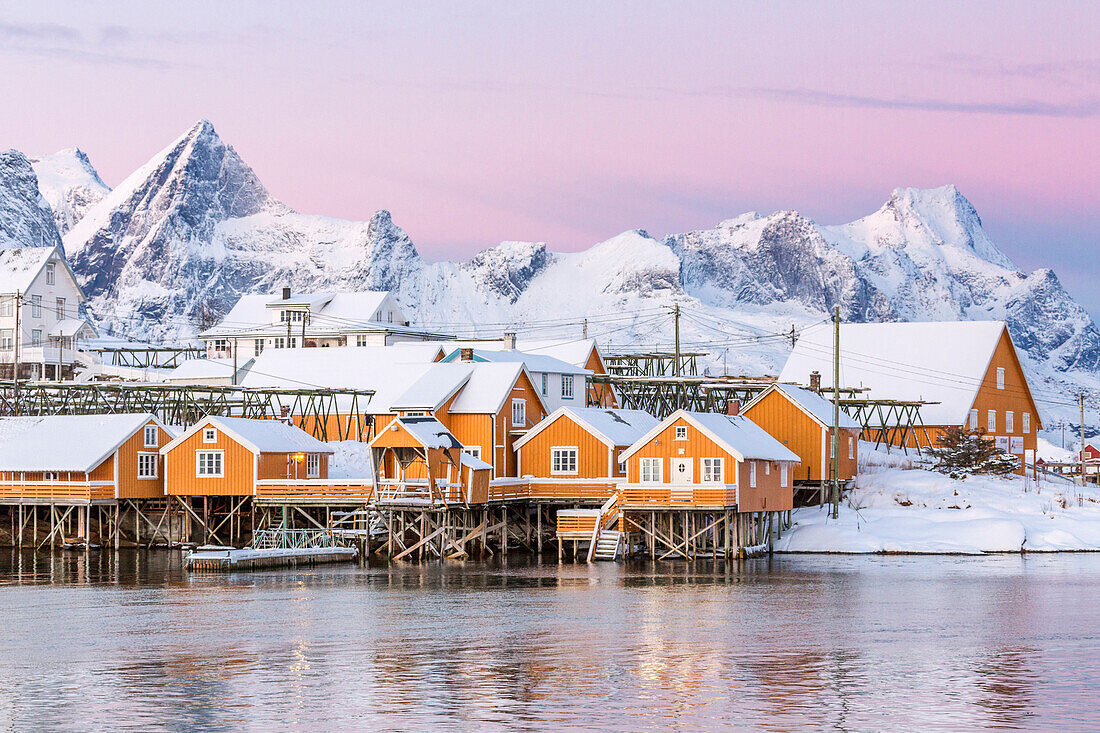 The colors of dawn frame the fishermen's houses surrounded by frozen sea, Sakrisoy, Reine, Nordland, Lofoten Islands, Arctic, Norway, Scandinavia, Europe