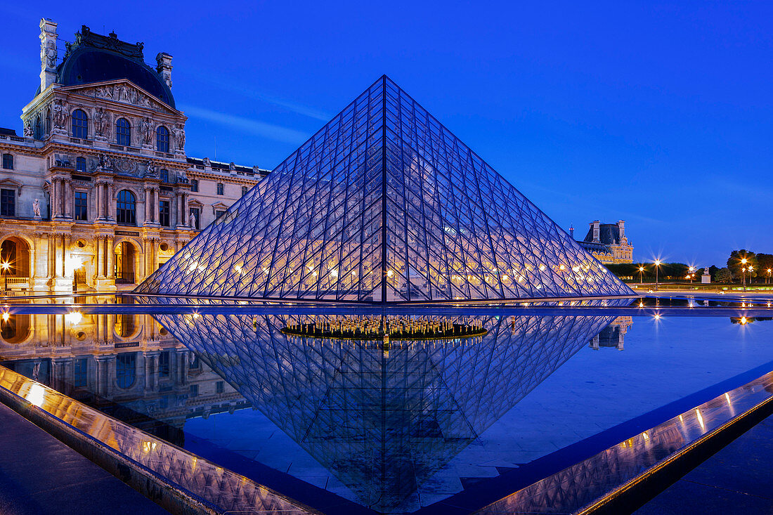 The Louvre Pyramid and Palace reflected in a still pool within the Napoleon Courtyard at twilight, Paris, France, Europe