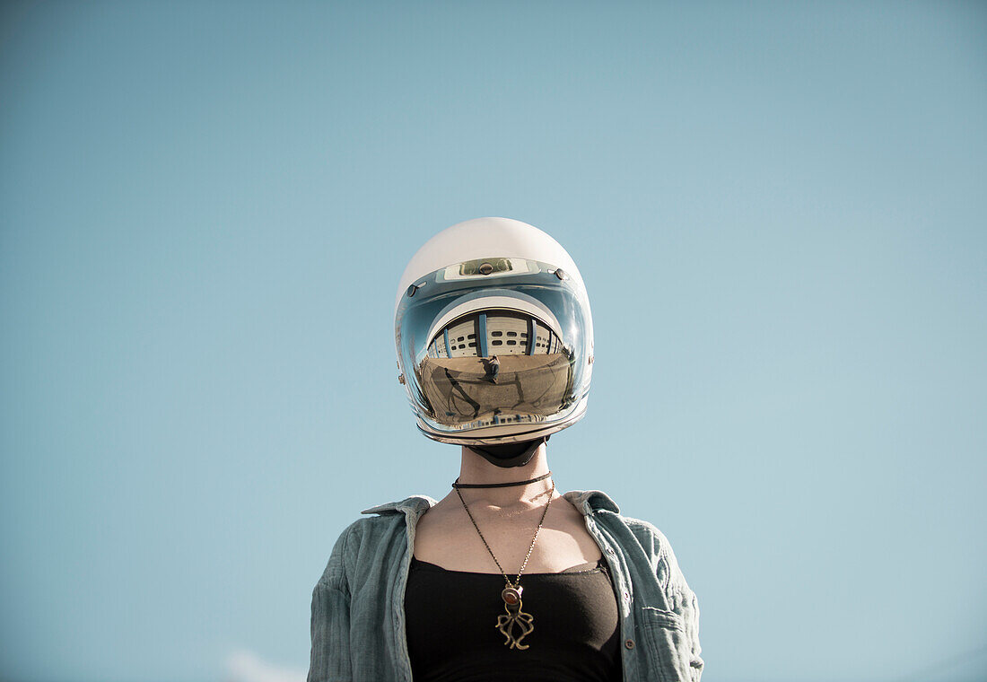 Centered perspective of a woman wearing a vintage motorcycle helmut with a reflection of a auto garage