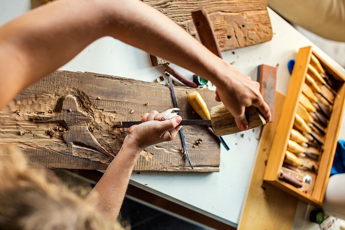 Young woman carves picture on wood