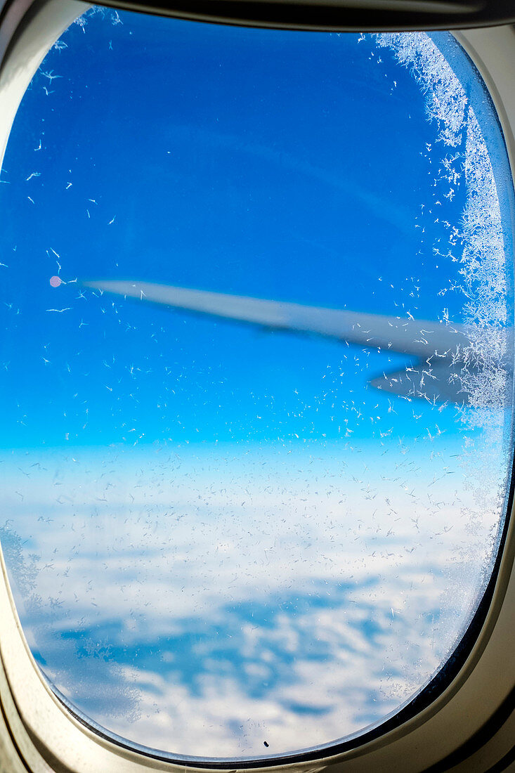 Blue sky and clouds, ice crystals on plane window flying over eastern Europe