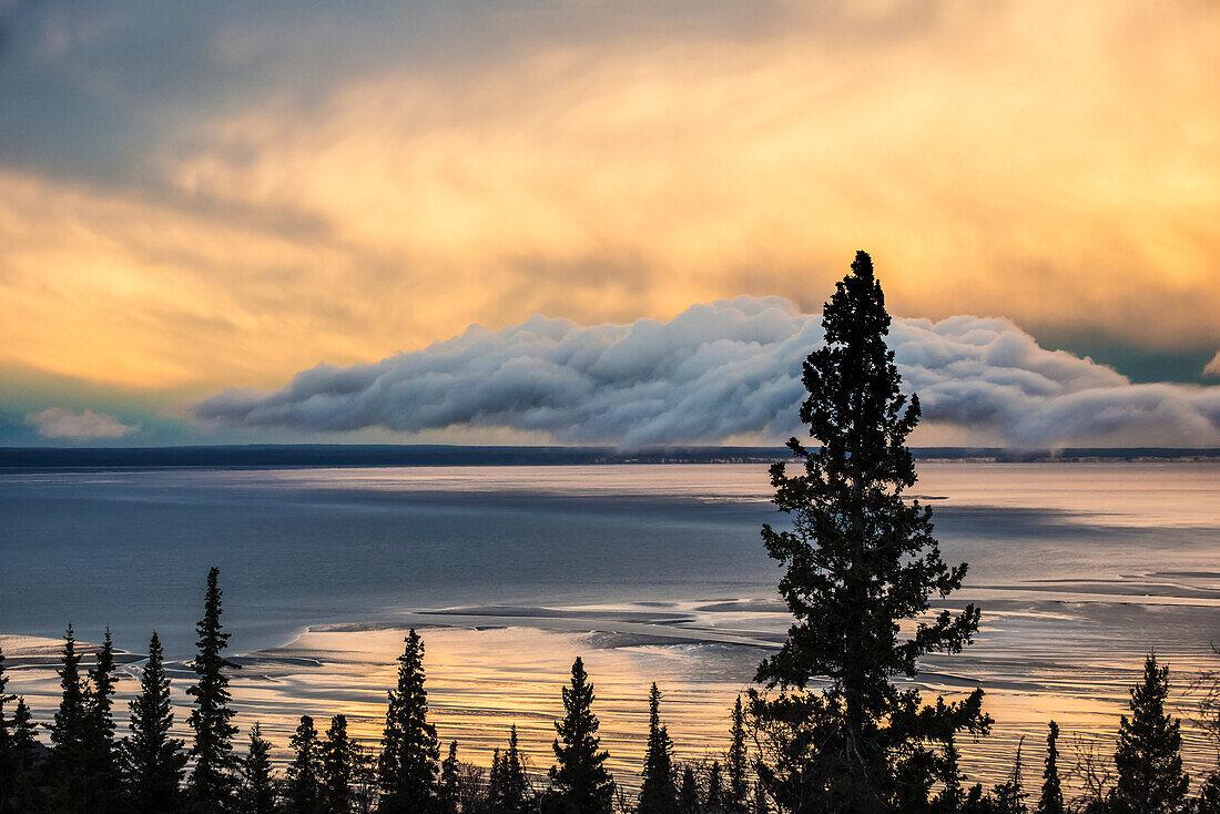 Setting sun sets the clouds aglow over Cook Inlet near Anchorage, Alaska.