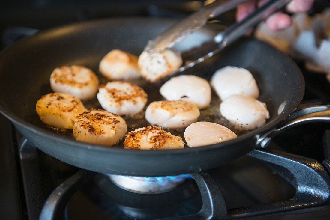 Scallops are sauteed in a skillet in preparation for dinner at the Katmai Wilderness Lodge in Kukak Bay, Katmai National Park & Preserve, Alaska.