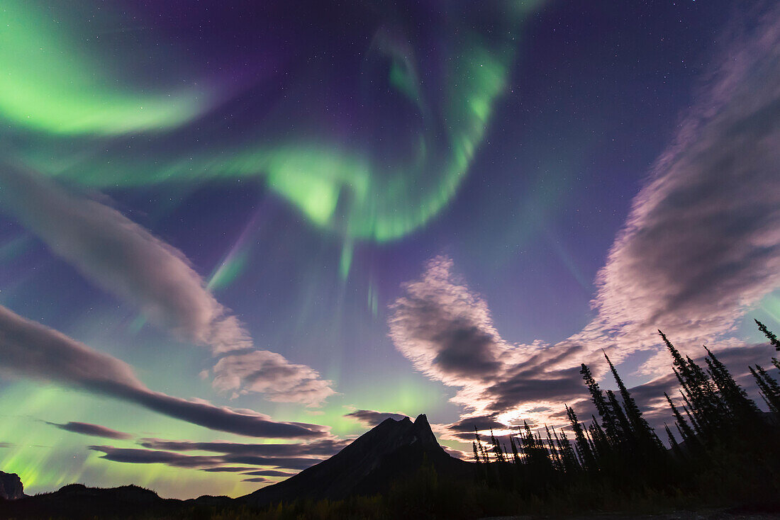 The aurora borealis and clouds share the sky over Mt. Sukakpak in the Brooks Range north of Wiseman, Arctic Alaska.