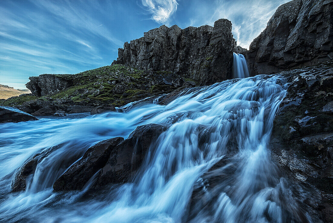 'A small waterfall flows into the ocean along the eastern coast of Iceland; Iceland'
