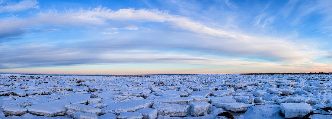 'Ice forms on the shores of Hudson Bay as sunset starts to light up the clouds; Churchill, Manitoba, Canada'