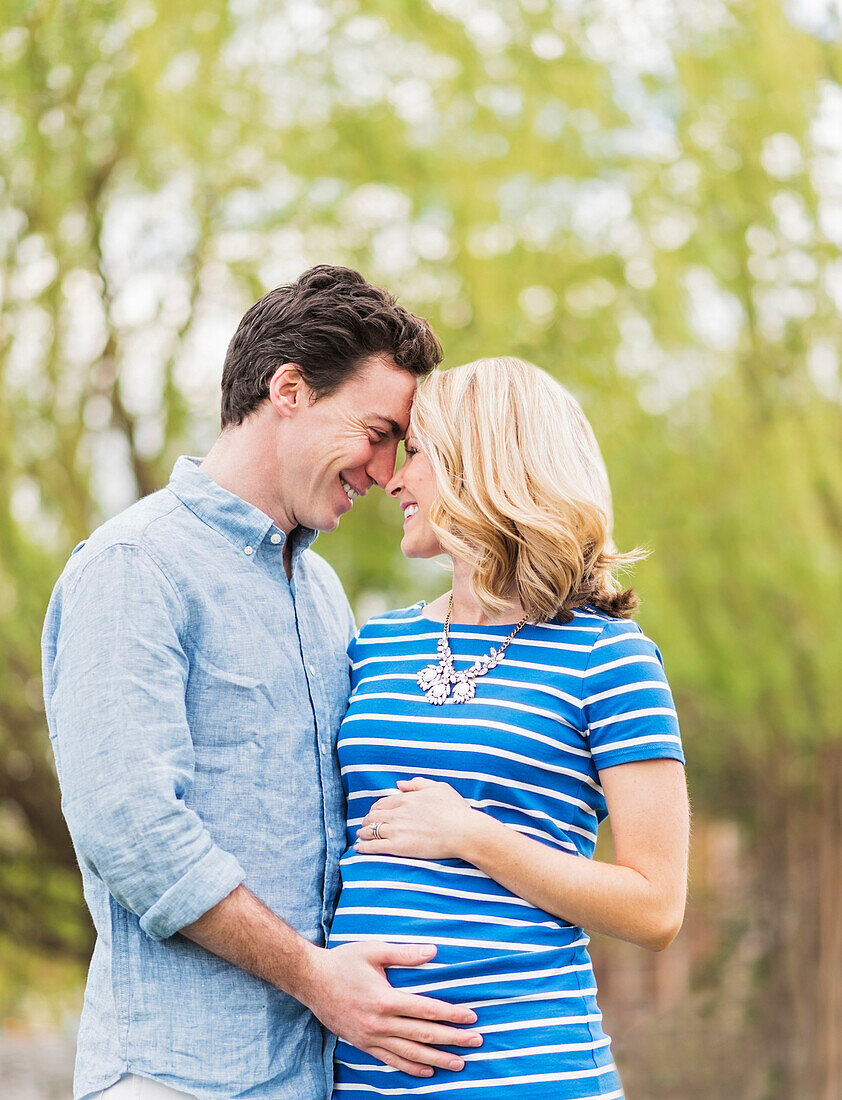 Smiling Caucasian man and expectant mother rubbing noses