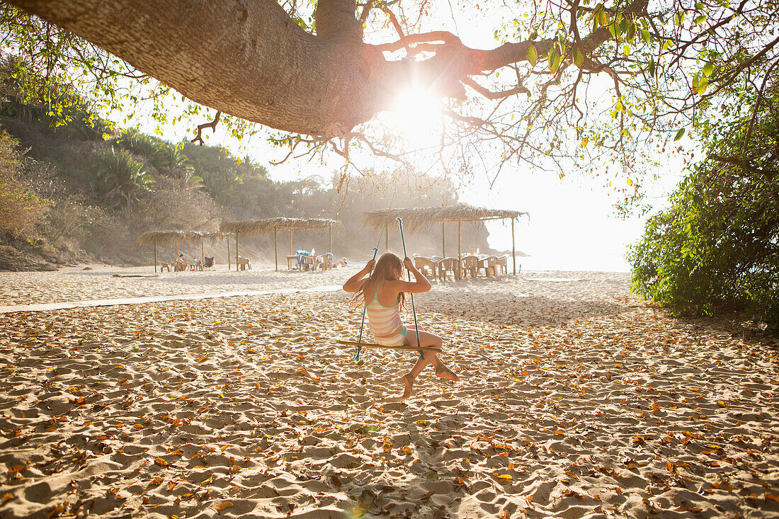 Caucasian girl sitting on tree swing