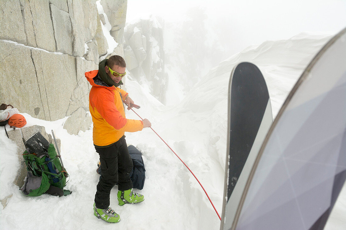 A man camped on the summit ridge after  climbing Thunderbolt Ridge in Hogum Fork while on a backcountry ski tour in Little Cottonwood Canyon, Lone Peak Wilderness, Uinta-Wasatch-Cache National Forest, Salt Lake City, Utah.