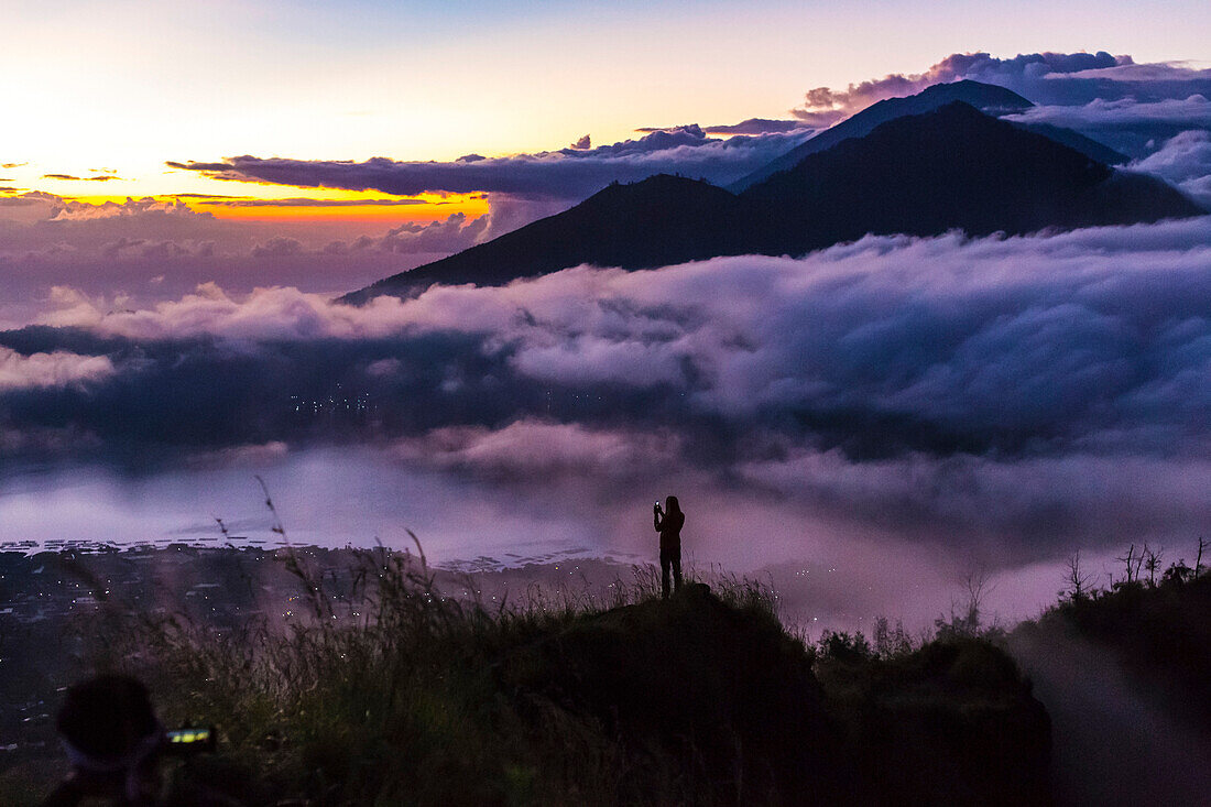 Man takes photos with smartphone in mountains at sunrise