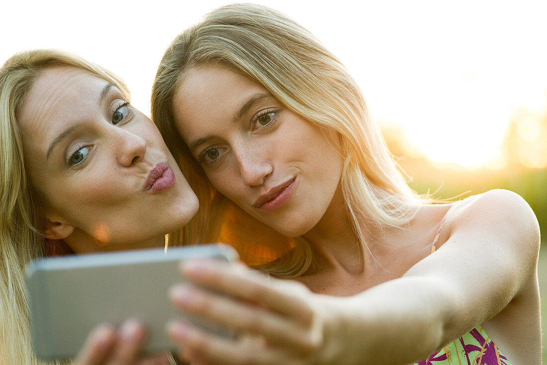 Couple posing cheek to cheek for smartphone selfie