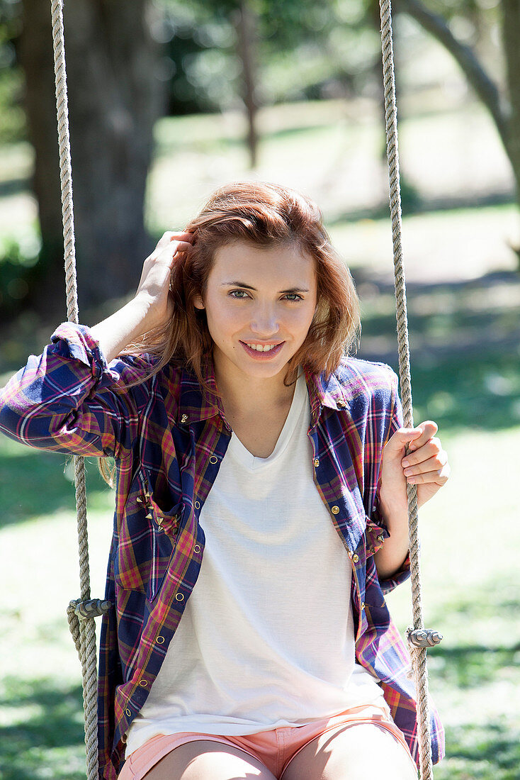 Young woman sitting on swing, portrait