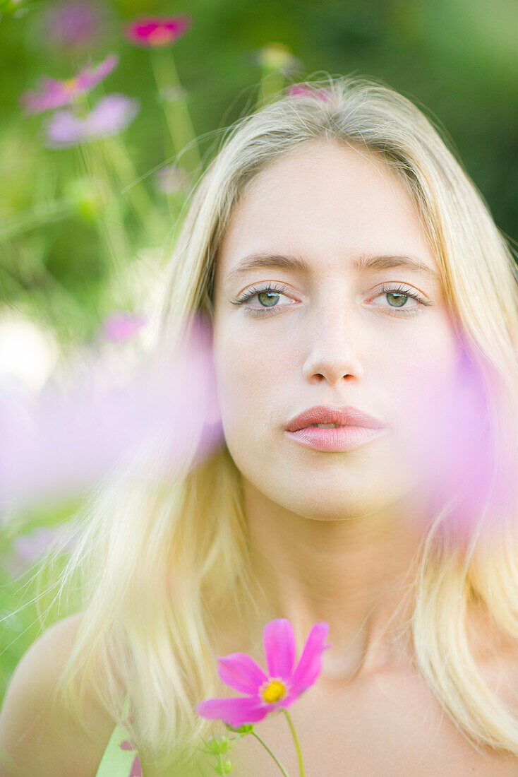 Young woman among cosmos flowers, portrait