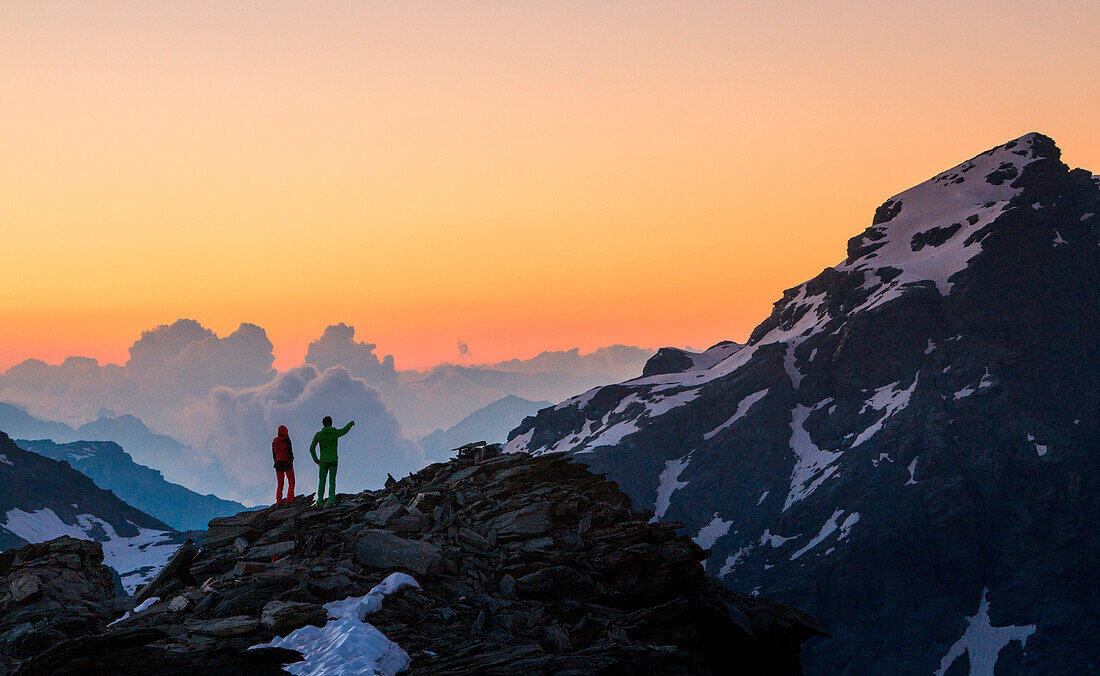 Two hikers at sunrise on the top of Forbici peak in Valmalenco. Valtellina - Lombardy.