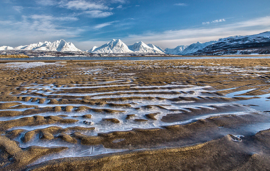 The icy sandy beach surrounding the snow capped mountains Breivikeidet Lyngen Alps Troms?© Lapland Norway Europe