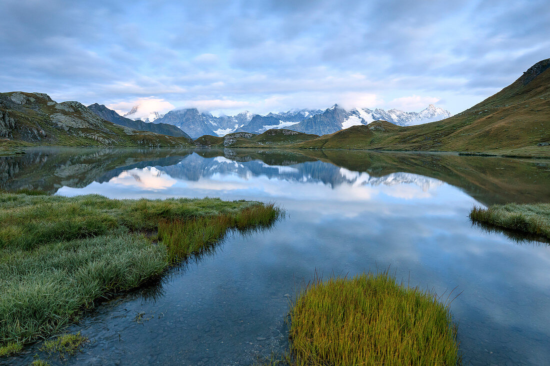 The mountain range is reflected in Fenetre Lakes at dusk Ferret Valley Saint Rh?®my Grand St Bernard Aosta Valley Italy Europe