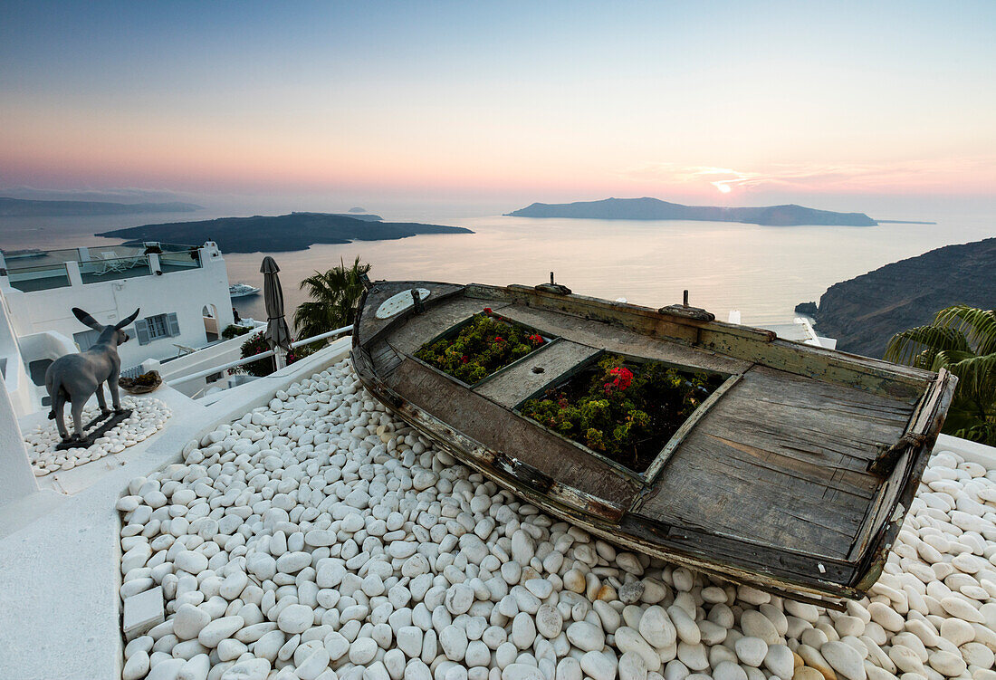 A wooden boat on the white stones overlooking the blue Aegean Sea before dusk at Firostefani Santorini Cyclades Greece Europe