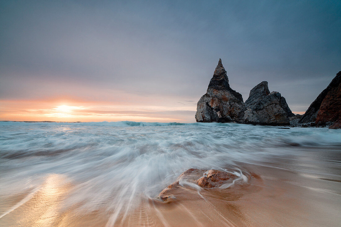 Ocean waves crashing on the beach of Praia da Ursa at sunset surrounded by cliffs Cabo da Roca Colares Sintra Portugal Europe