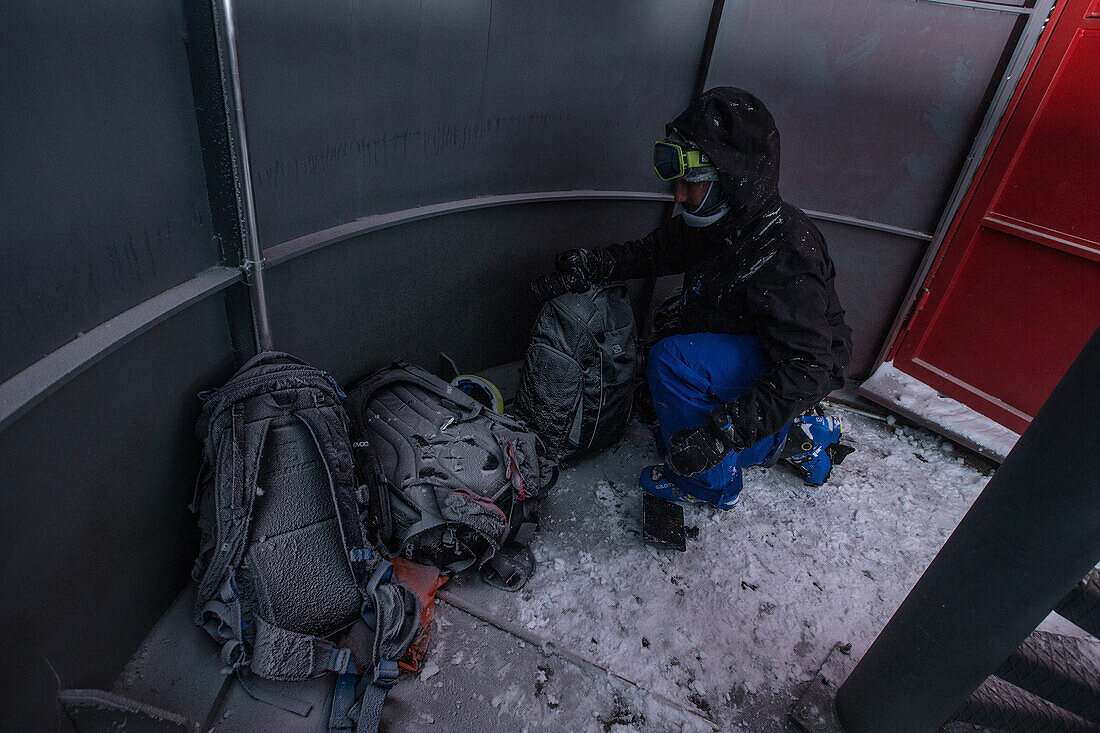 Young man get snow-covered bags out of a ski lift, Andermatt, Uri, Switzerland