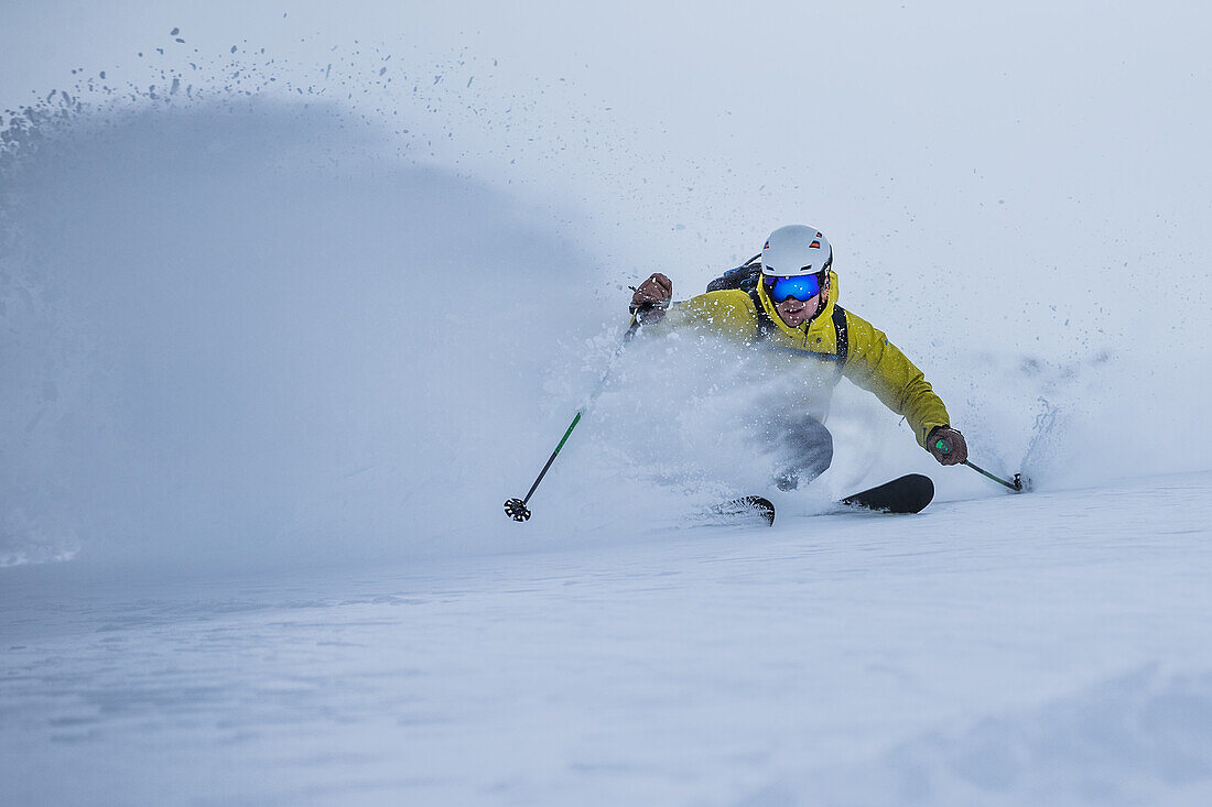 Young male skier riding through deep powder snow apart the slope, Andermatt, Uri, Switzerland