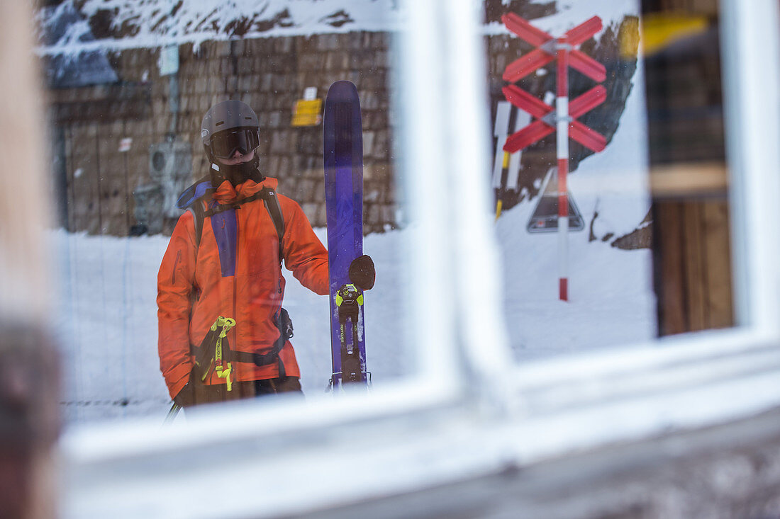 Young male skier standing at a railroad crossing, Andermatt, Uri, Switzerland