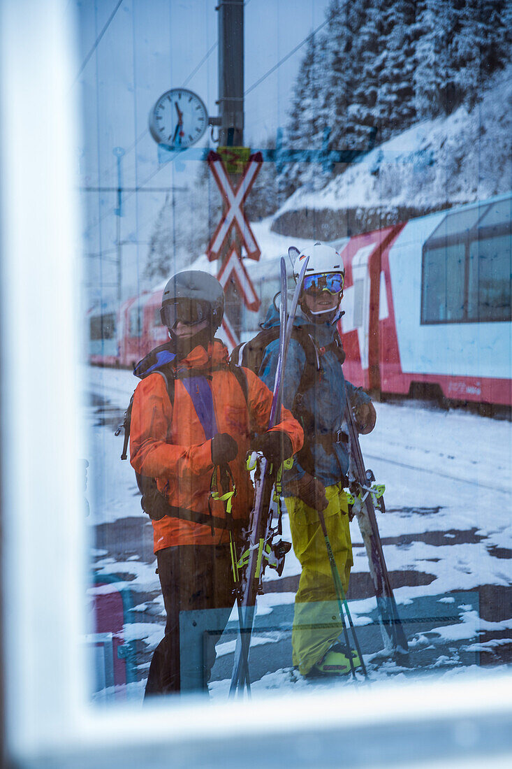Two young male skier standing at a railroad crossing, Andermatt, Uri, Switzerland