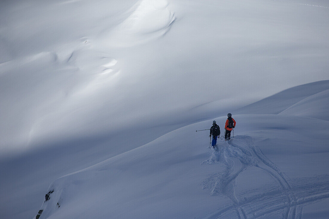 Two young skiers planing their next line in the deep powder snwo apart the slopes, Andermatt, Uri, Switzerland