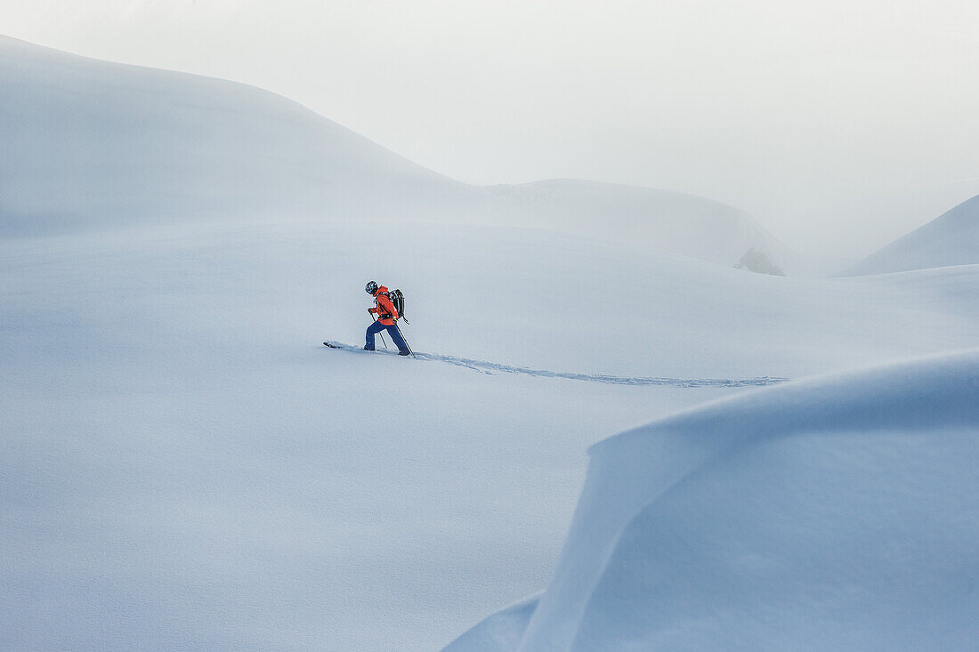 Junger Skifahrer läuft durch den Tiefschnee abseits der Pisten, Andermatt, Uri, Schweiz