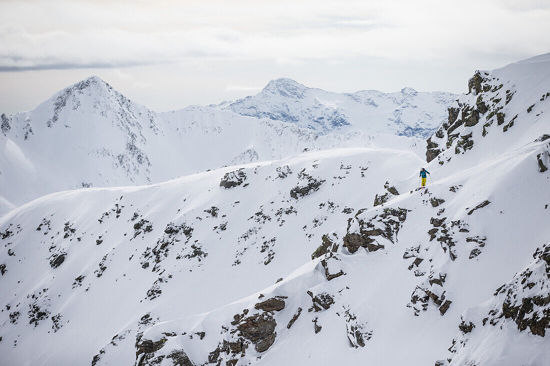 Junger Skifahrer steht abseits der Piste im Tiefschnee, Andermatt, Uri, Schweiz