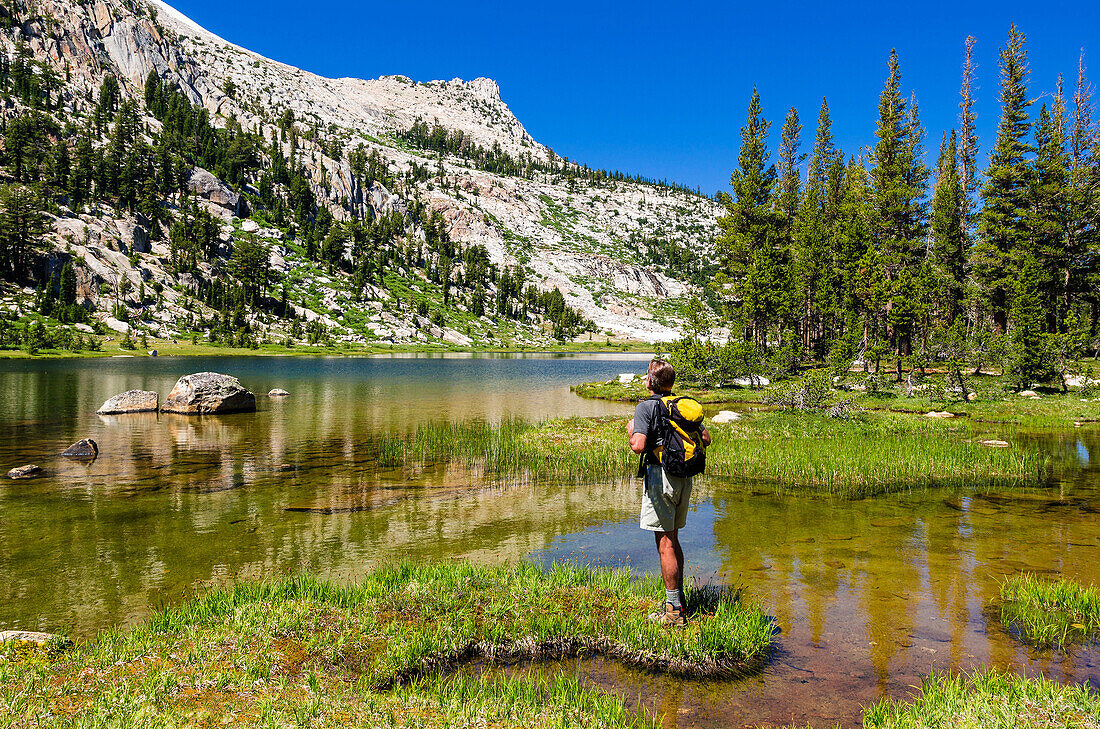 Hiker at Elizabeth Lake under Unicorn Peak, Tuolumne Meadows, Yosemite National Park, California USA.