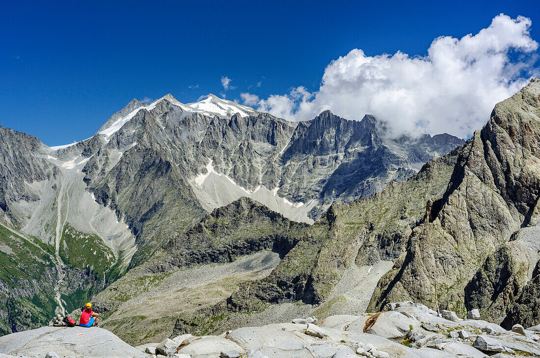 Woman sitting on rockslab and looking towards Cima Presanella, hut rifugio Lobbia Alta, Val Genova, Adamello-Presanella Group, Trentino, Italy