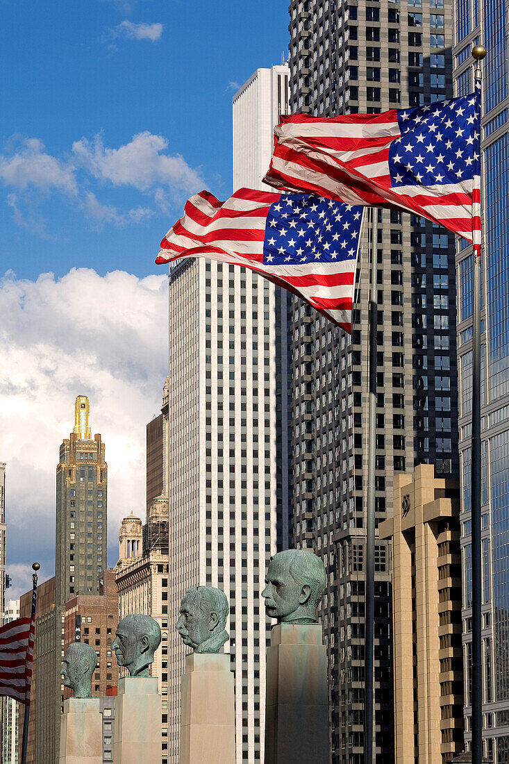 USA, Illinois, Chicago, an der Unterseite Büsten von Geschäftsleuten von Merchandise Mart, amerikanische Flaggen und im Hintergrund die Wolkenkratzer von West Wacker Drive