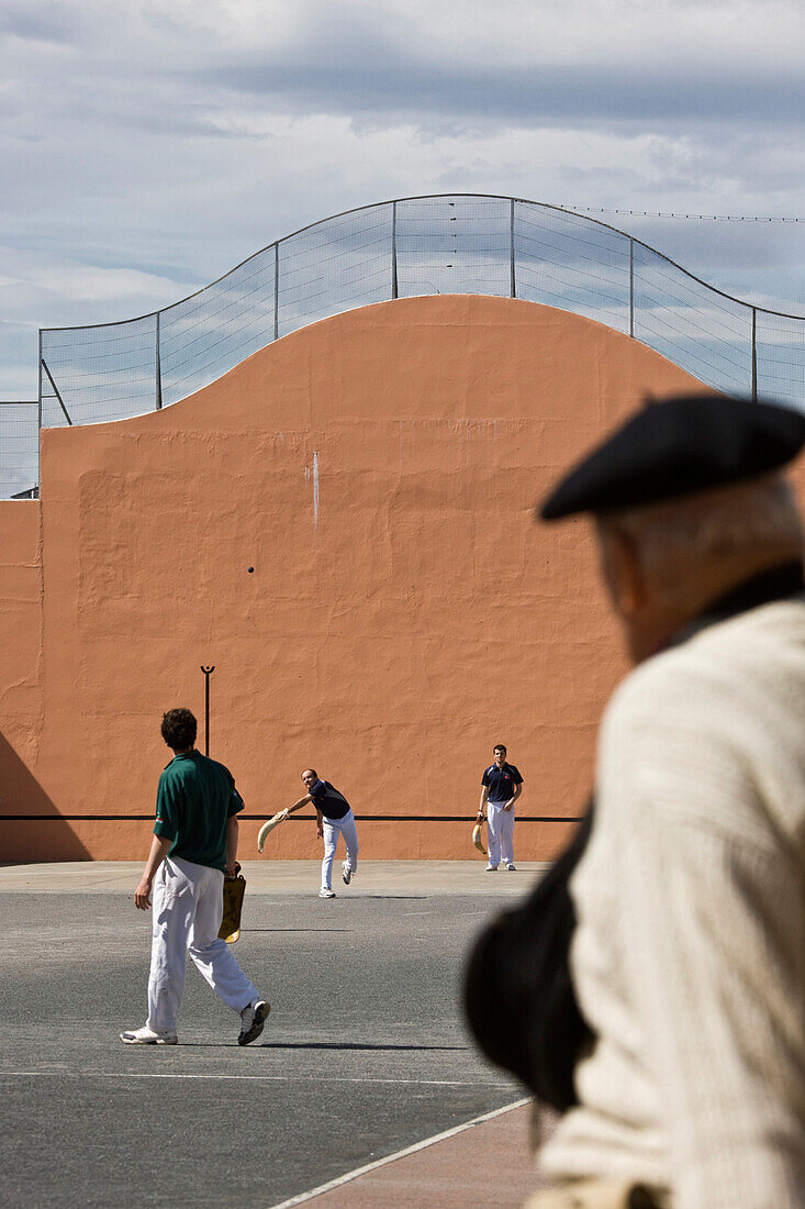 France, Pyrenees Atlantiques, Saint Jean de Luz, man watching a Basque pelota match played in a wall called fronton